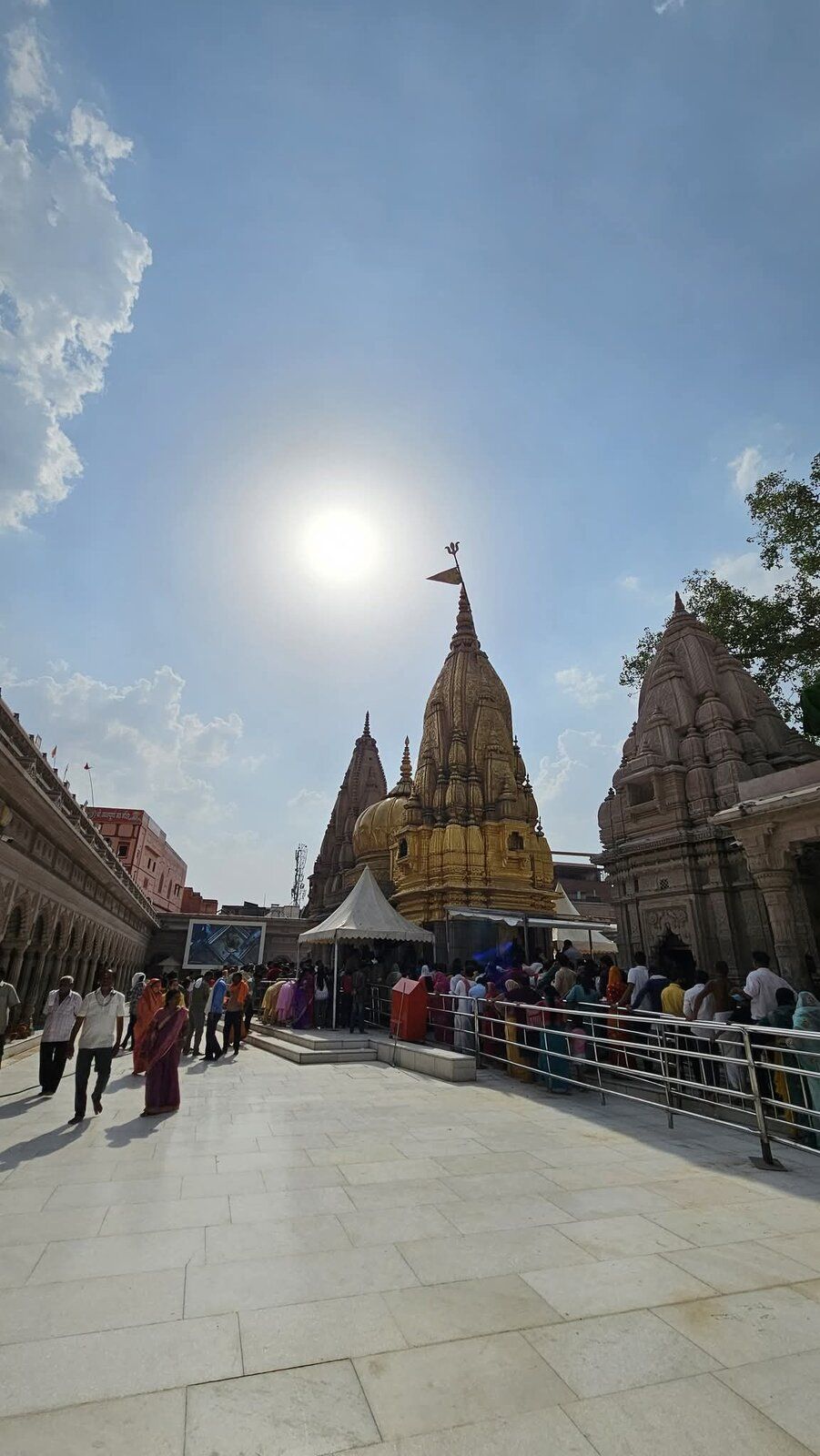 The stone courtyard in daylight with the temple's gold spire under a bright sun